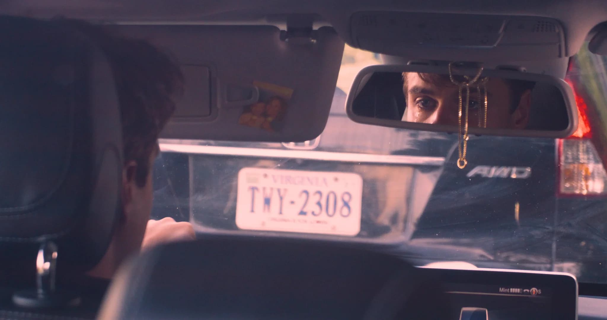 A grieving man reflected in a car's rearview mirror